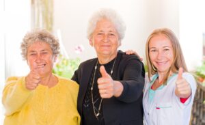 two elderly women and one young girl giving a thumbs up