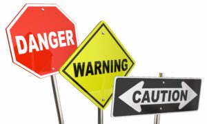 Three signs reading "danger", "warning", and "caution"