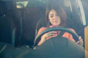 Asian woman checking her phone while driving