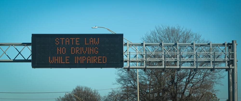 An overhead highway sign reminds drivers that no driving while impaired is state law