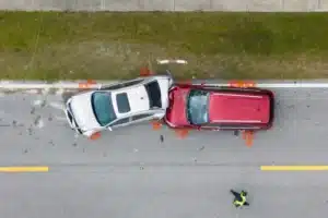 A police officer walks toward two cars after a collision, a silver car, in the front, is being declared a totaled car, the picture is taken on a Florida highway.