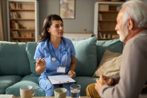 Female nurse talking with mature man during her home visit.