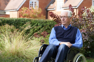 A nursing home resident sits outside near the facility building. If you suspect nursing home neglect, protect your loved one and report the situation to the authorities.